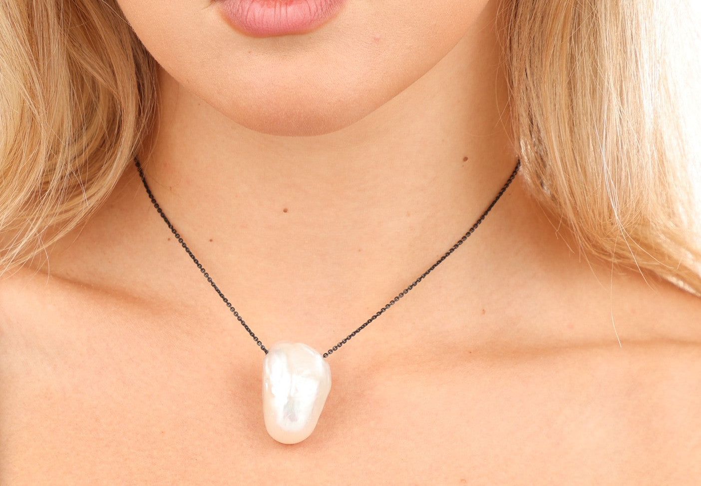 Elegant pearl necklace showcasing a lustrous freshwater pearl pendant on a sleek black chain.