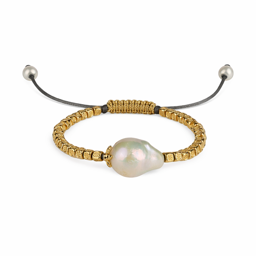 An adjustable gold-plated bracelet with small gold-plated balls and a baroque freshwater pearl in the center, featuring a black leather strap and two small freshwater pearls in gold-plated finishes at the ends.