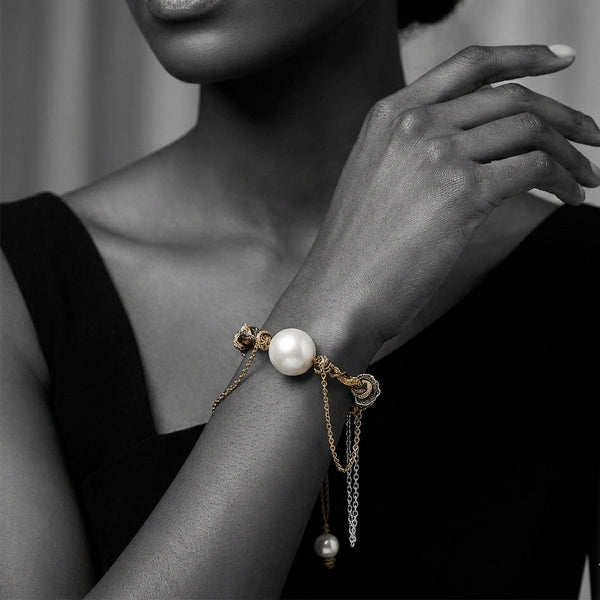 A bracelet featuring a round freshwater pearl centerpiece, surrounded by gold and silver plated chains.