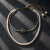 Adjustable freshwater pearl necklace with labradorite beads and an emerald centerpiece, flatlay on dark slate — JLL Pearl