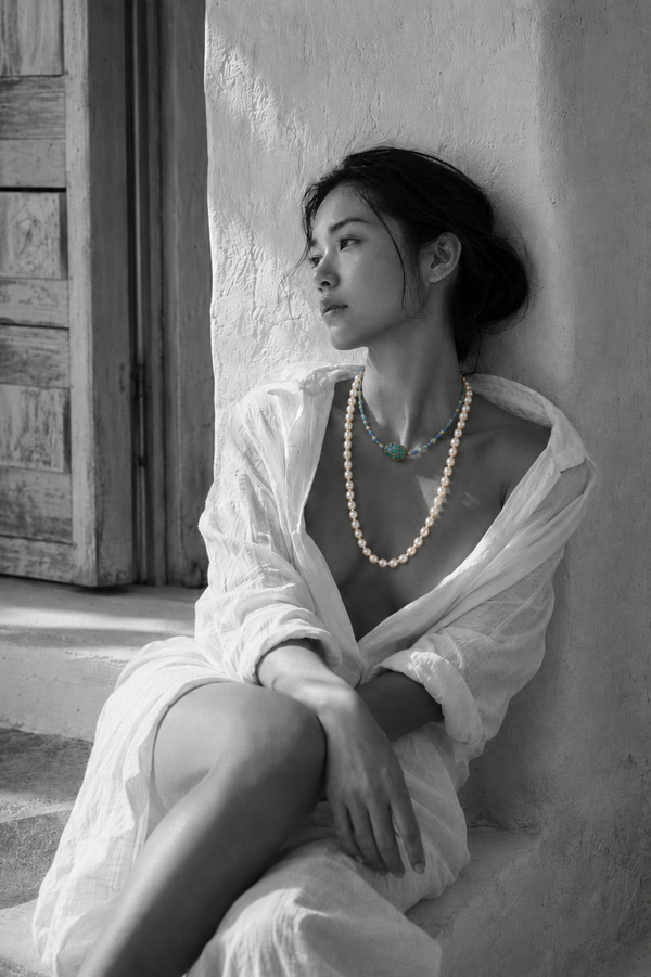 Woman wearing a freshwater pearl necklace with an emerald and diamond centerpiece, black and white portrait — JLL Pearl