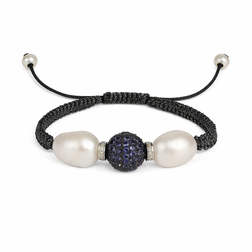 A bracelet featuring two round freshwater pearls, two sparkling diamond bicones, and a ball of blue sapphires set in silver, with black macrame thread and pearl beads.