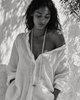 Long baroque pearl necklace worn full length on a model in white linen, Mediterranean light, garnet ornament in deep red