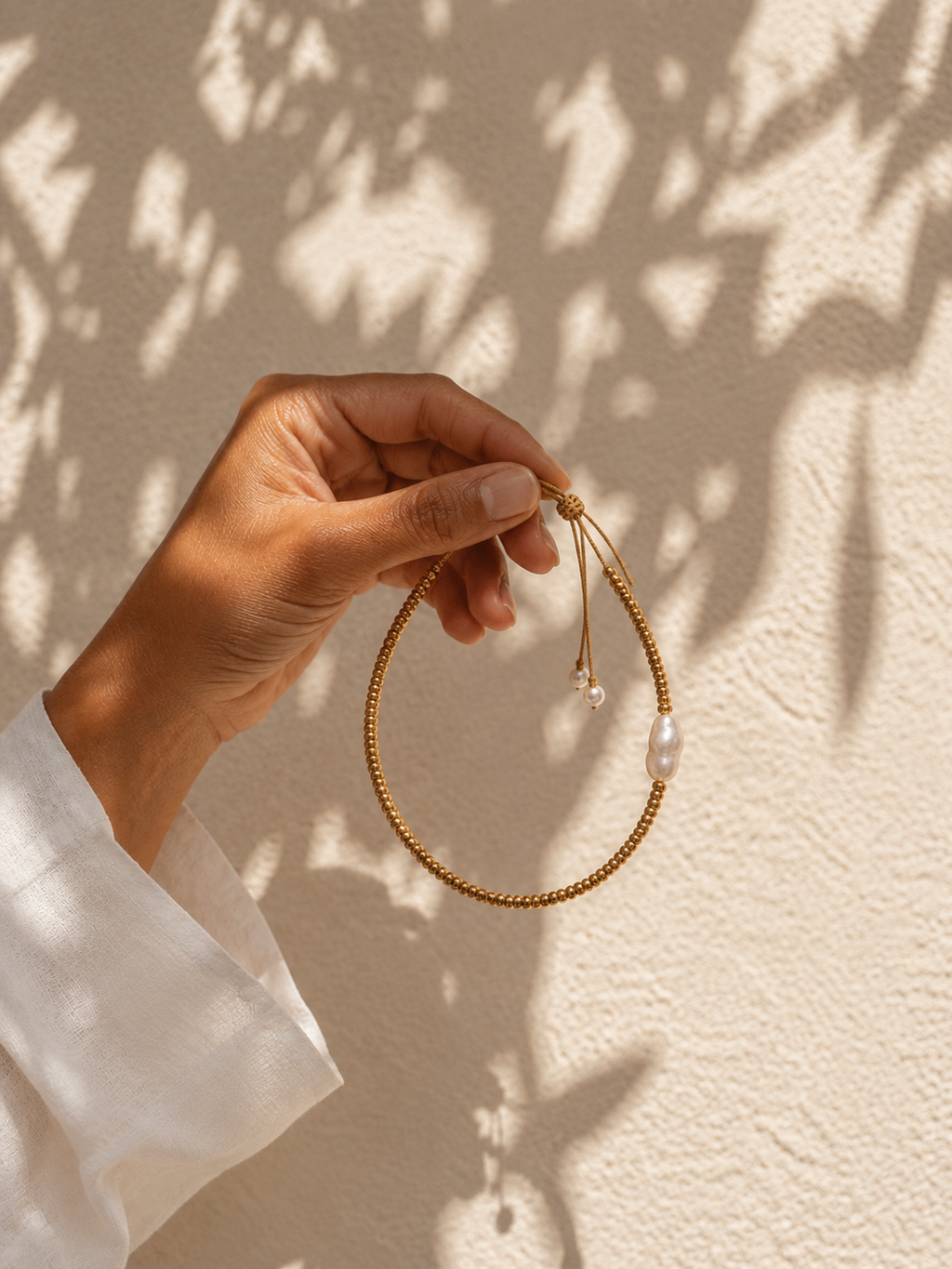 Hand holding Arabelle baroque pearl and gold cube necklace, full necklace length — JLL Pearl