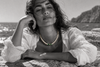 Bao freshwater pearl necklace peridot diopside worn by a woman lying on a rock by the Aegean Sea, black and white editorial photograph with selective color on jewelry, JLL Pearl