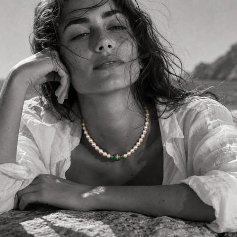 Bao freshwater pearl necklace peridot diopside worn by a woman lying on a rock by the Aegean Sea, black and white editorial photograph with selective color on jewelry, JLL Pearl