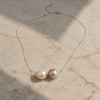 Bocca baroque pearl necklace silver chain flatlay on aged marble, two baroque freshwater pearls in cream and pink-mauve with fine silver chain and lobster clasp visible, natural sunlight, JLL Pearl