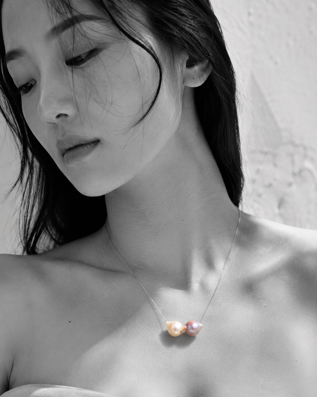 Bocca baroque pearl necklace silver chain worn by Asian model, selective color portrait, two mismatched freshwater pearls in cream and pink-mauve against black and white skin, handmade by JLL Pearl in Greece
