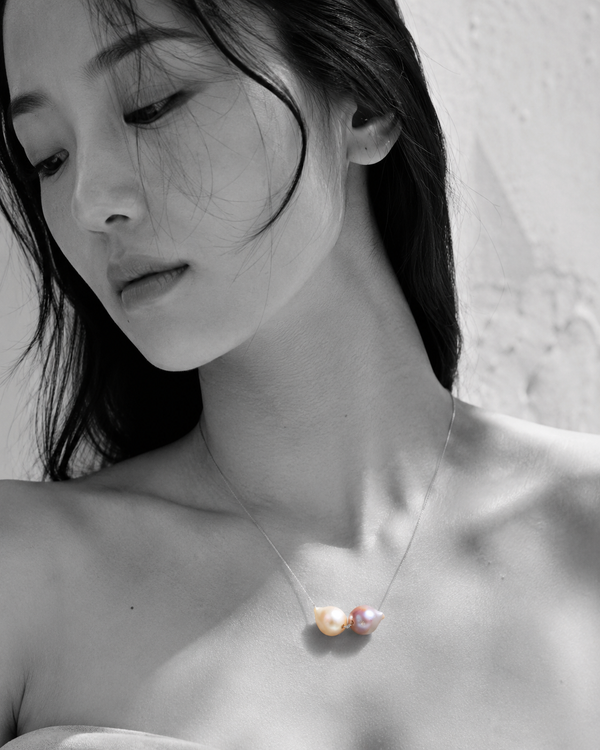 Bocca baroque pearl necklace silver chain worn by Asian model, selective color portrait, two mismatched freshwater pearls in cream and pink-mauve against black and white skin, handmade by JLL Pearl in Greece
