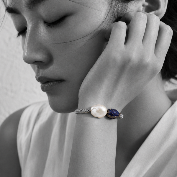 Black and white portrait of a baroque pearl bracelet with a pavé sapphire bead against the cheek — JLL Pearl