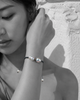 Butterfly macramé bracelet with baroque grey pearls — black and white portrait, Asian woman, Greek stone wall