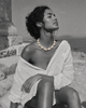 Eden baroque pearl gold flower choker worn against ancient Greek ruins, woman seated on stone steps with eyes closed facing the Aegean sea, selective colour necklace against black and white scene, handmade by JLL Pearl