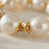 Close-up of Ella choker gold flower cap between two large round white baroque freshwater pearls on nude satin cord