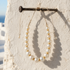 Ella round pearl gold flower choker hanging from iron nail on whitewashed Greek wall, eighteen graduated pearls — JLL Pearl
