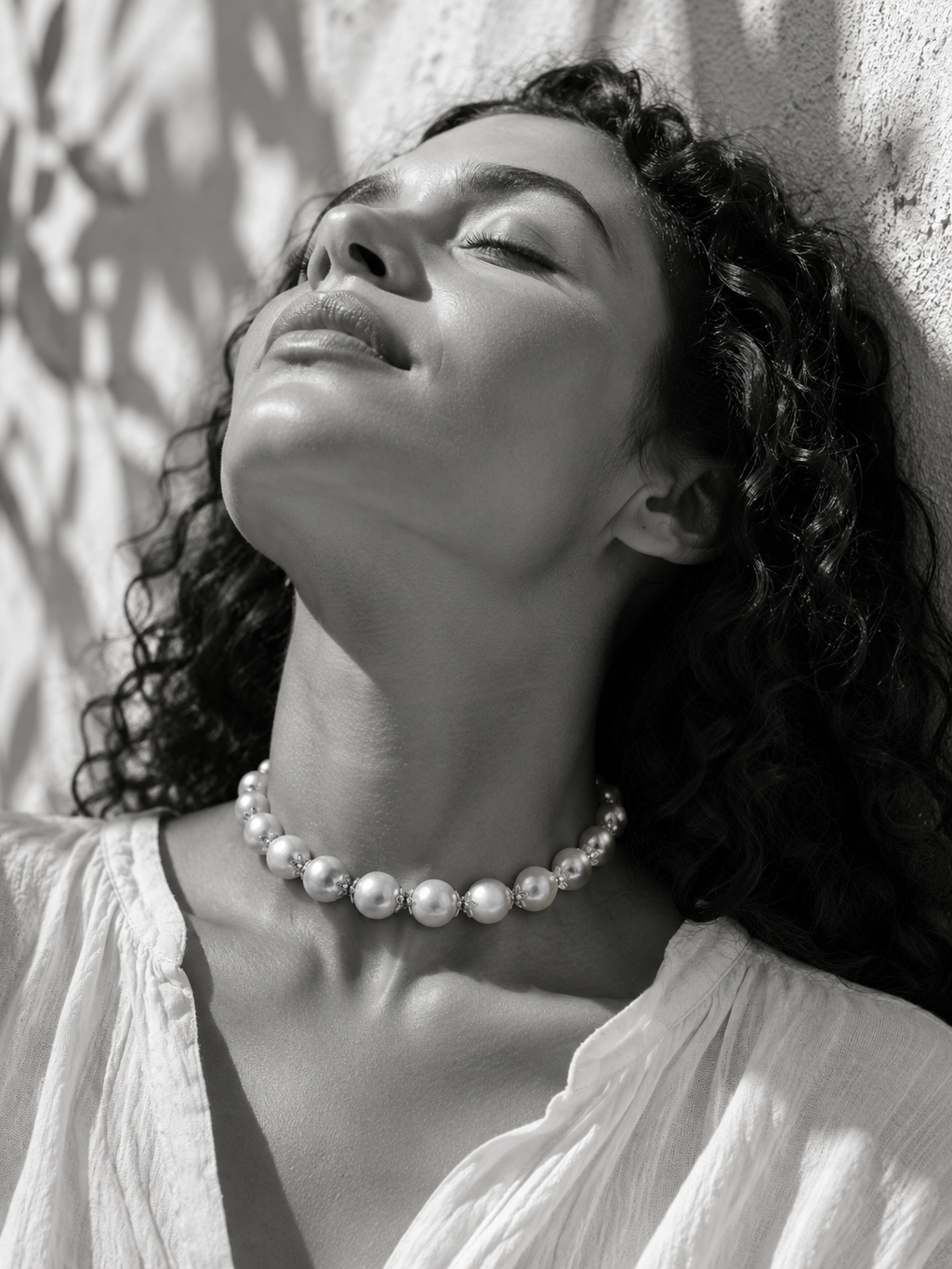 Woman wearing Ella round pearl gold flower choker at the throat, black and white Mediterranean light portrait — JLL Pearl