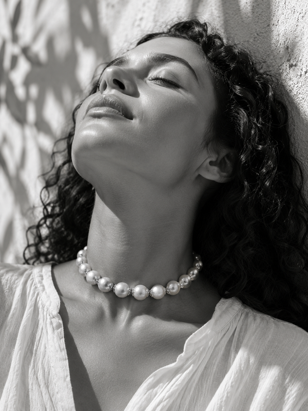 Woman wearing Ella round pearl gold flower choker at the throat, black and white Mediterranean light portrait — JLL Pearl