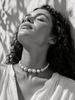 Woman wearing Ella round pearl gold flower choker at the throat, black and white Mediterranean light portrait — JLL Pearl