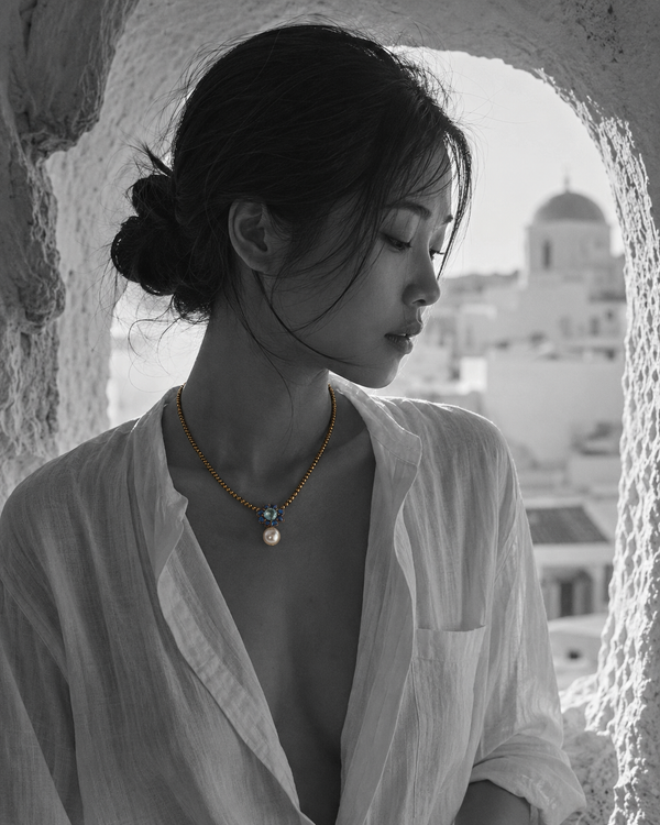Flowerdream freshwater pearl hematite topaz necklace worn by an Asian model in a Greek stone arch, Santorini in background, B&W with necklace in natural colour on décolleté, handmade by JLL Pearl