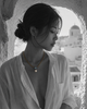 Flowerdream freshwater pearl hematite topaz necklace worn by an Asian model in a Greek stone arch, Santorini in background, B&W with necklace in natural colour on décolleté, handmade by JLL Pearl