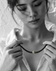 Hydra black onyx peridot necklace held in both hands by Asian model, face softly out of focus looking down, peridot sphere in natural green, whitewashed wall, handmade by JLL Pearl