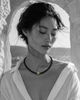 Hydra black onyx peridot necklace worn by Asian model in whitewashed stone arch, eyes closed, white linen shirt, peridot sphere in natural celadon green, handmade by JLL Pearl