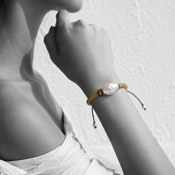 Black and white portrait of a baroque pearl bracelet on woven gold cord with pearl-tipped ties — JLL Pearl