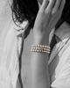 Three-strand pearl bracelet with grey macramé cord and silver star on wrist, black and white portrait