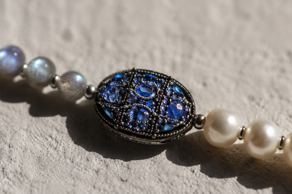 Close-up of Lola freshwater pearl labradorite necklace, oxidized silver oval connector set with sapphire fragments between 10mm white pearls and 6mm grey-blue labradorite beads, handmade by JLL Pearl