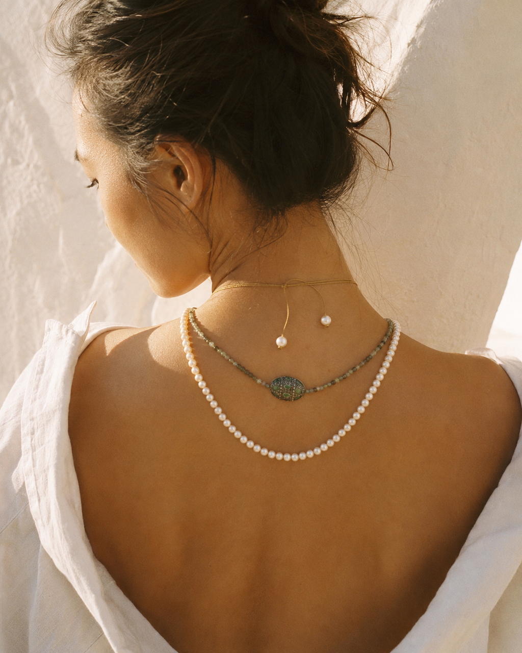 Lola freshwater pearl labradorite necklace at the nape of an Asian model, lasso cord detail visible against bare skin, warm Greek afternoon light, handmade by JLL Pearl