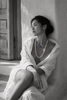 Lola freshwater pearl labradorite necklace worn by an Asian model seated near a Greek window, both strands on bare décolleté, oxidized silver connector in colour against black and white, handmade by JLL Pearl