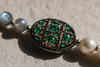 Macro detail of an emerald and champagne diamond centerpiece on a freshwater pearl necklace — JLL Pearl
