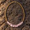 Mani rose amethyst pyrite necklace flatlay on dark volcanic rock, five faceted rose amethyst chunks graduating in size, gold-plated ball beads, lobster clasp, handmade in Greece by JLL Pearl