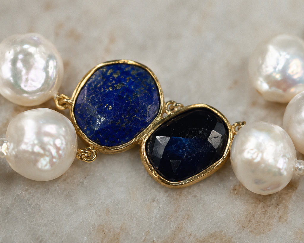 Close-up of Nati necklace connector, lapis lazuli oval and dark faceted sapphire set in gold bezel, white baroque freshwater pearls on either side, JLL Pearl