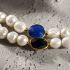 Close-up of Nati necklace connector, lapis lazuli oval and dark faceted sapphire set in gold bezel, white baroque freshwater pearls on either side, JLL Pearl