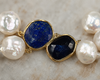 Close-up of Nati necklace connector, lapis lazuli oval and dark faceted sapphire set in gold bezel, white baroque freshwater pearls on either side, JLL Pearl