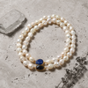Nati pearl necklace lapis lazuli sapphire gold arranged on pale travertine stone with cobalt blue sea glass and dried thyme, JLL Pearl