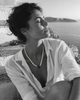 Nati pearl necklace lapis lazuli sapphire gold worn by a woman on white marble steps by the Aegean Sea, black and white editorial photograph, JLL Pearl