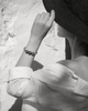 Black and white portrait of woman adjusting hat, Paros Tahitian pearl macramé bracelet in selective colour on wrist, Greek wall