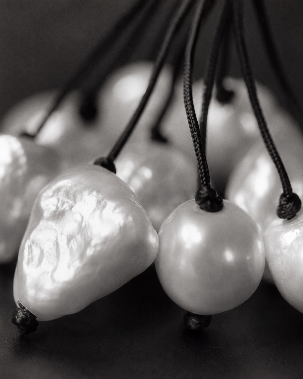 Close-up of Peipei baroque pearl cluster necklace, large baroque freshwater pearls showing varied shapes and iridescent surfaces, individual grey satin cord strands, black and white macro photography, JLL Pearl