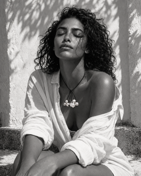 Peipei baroque pearl cluster necklace worn against a whitewashed Mediterranean wall, dappled leaf shadows, woman with eyes closed in white linen shirt, black and white editorial portrait, handmade by JLL Pearl