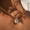 Close-up of Romy white topaz pendant in gold halo setting on gold hematite beaded chain, resting against warm dark skin, natural Mediterranean light, handmade by JLL Pearl
