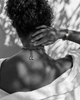 Samos braided silver gold chain pearl choker worn from behind, sliding knot closure with pearl finials at nape, matching Samos bracelet on wrist, olive leaf shadows on whitewashed wall, handmade by JLL Pearl