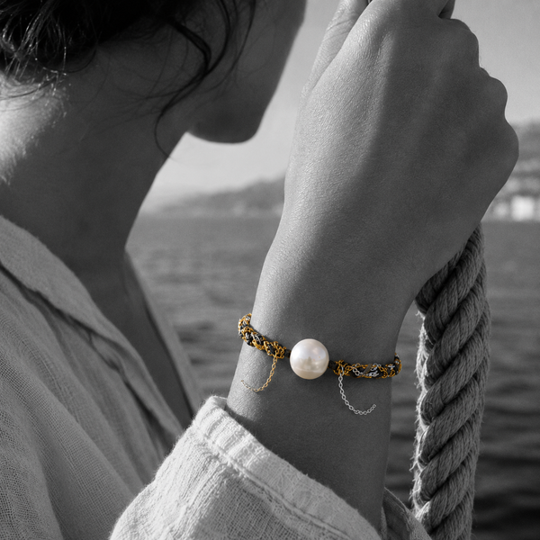 Black and white portrait of a round pearl bracelet on braided cord with draped fine chains — JLL Pearl