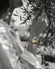 Tama bracelet — round freshwater pearl and gold macramé on wrist, olive branch background, black and white photograph with selective colour on bracelet