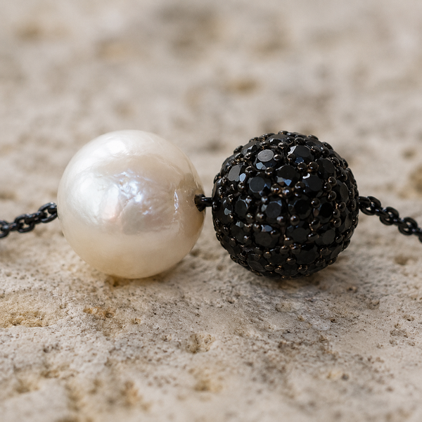 Zephyr pearl necklace black spinel detail, round white freshwater pearl and black pavé spinel sphere on pale sandstone, extreme close-up, handmade by JLL Pearl