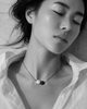 Zephyr pearl necklace black spinel oxidized silver worn by Asian model lying on marble, eyes closed, white linen shirt open, Mediterranean light, handmade by JLL Pearl